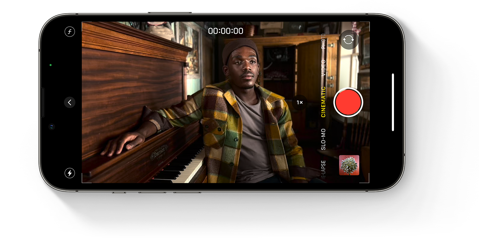Pantalla del iPhone que muestra la app Cámara en modo Vídeo Cinematográfico con una persona sentada al piano