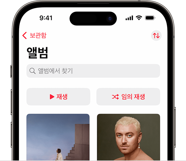 Apple Music 앱의 보관함 탭에 있는 앨범 상단에 임의 재생 버튼이 표시된 iPhone